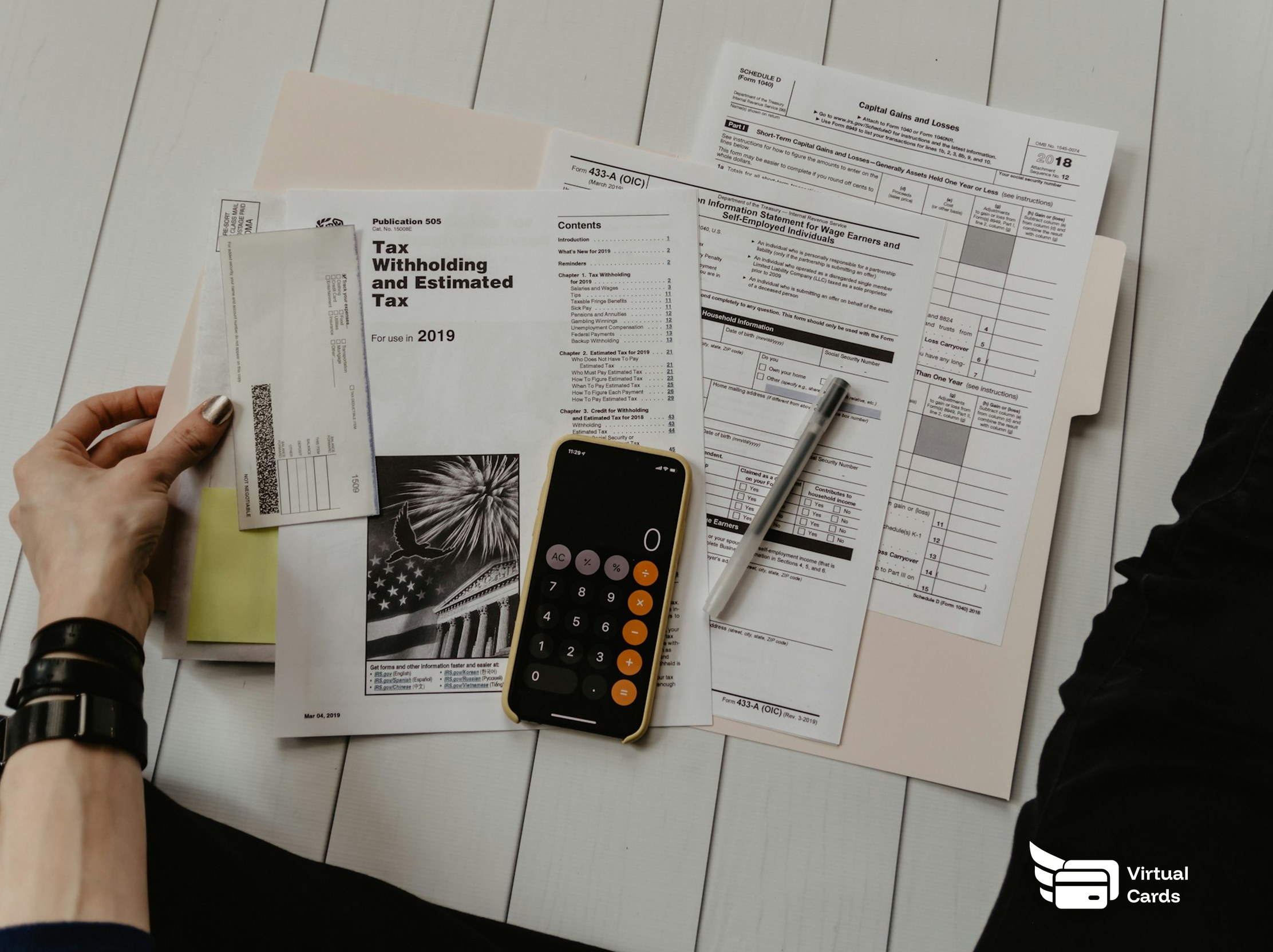 A calculator and pen resting on printed tax forms and statements.