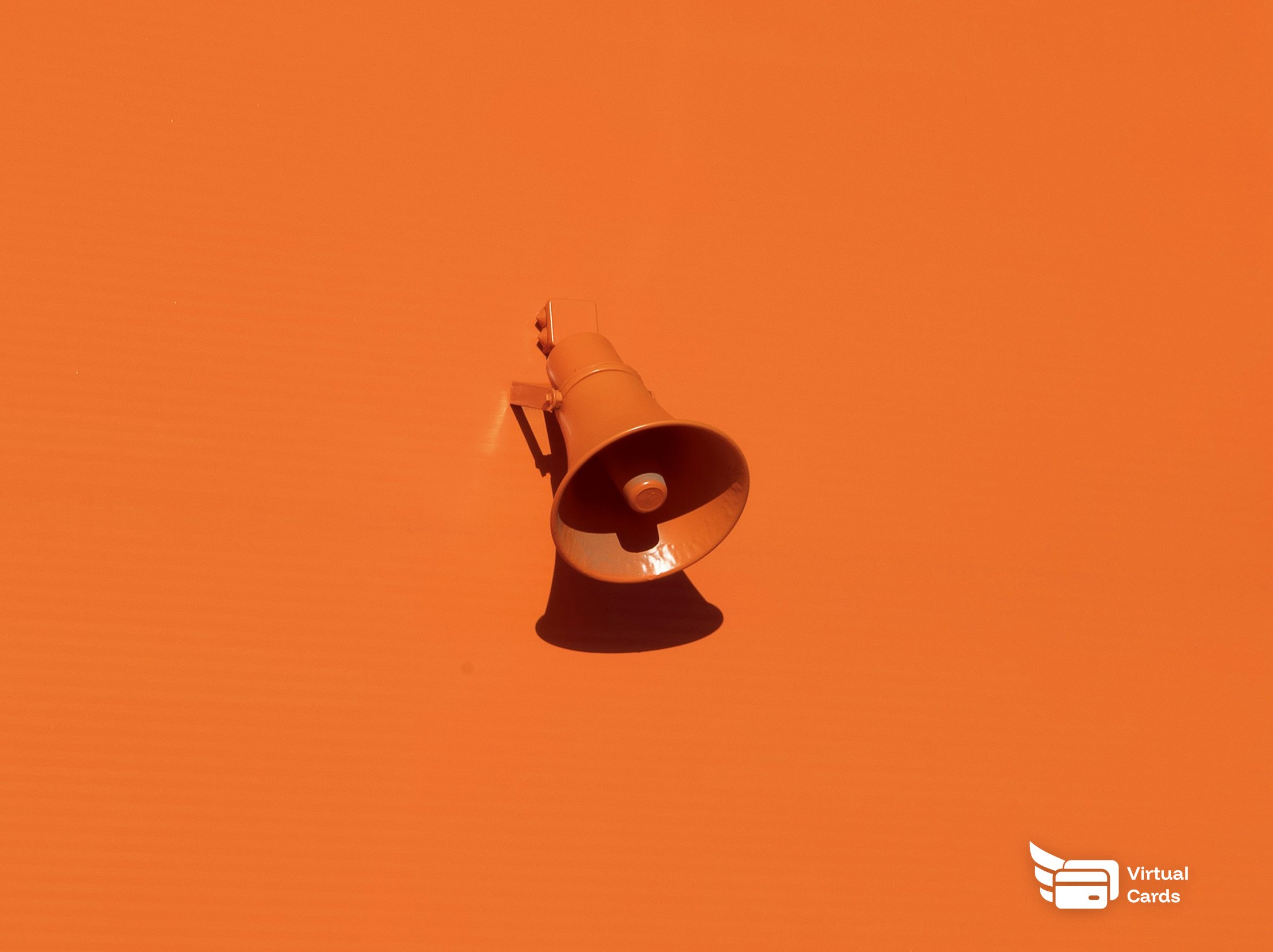 A bright orange megaphone on an orange background, representing advertising and marketing spend kept in check with capped virtual Visa cards.