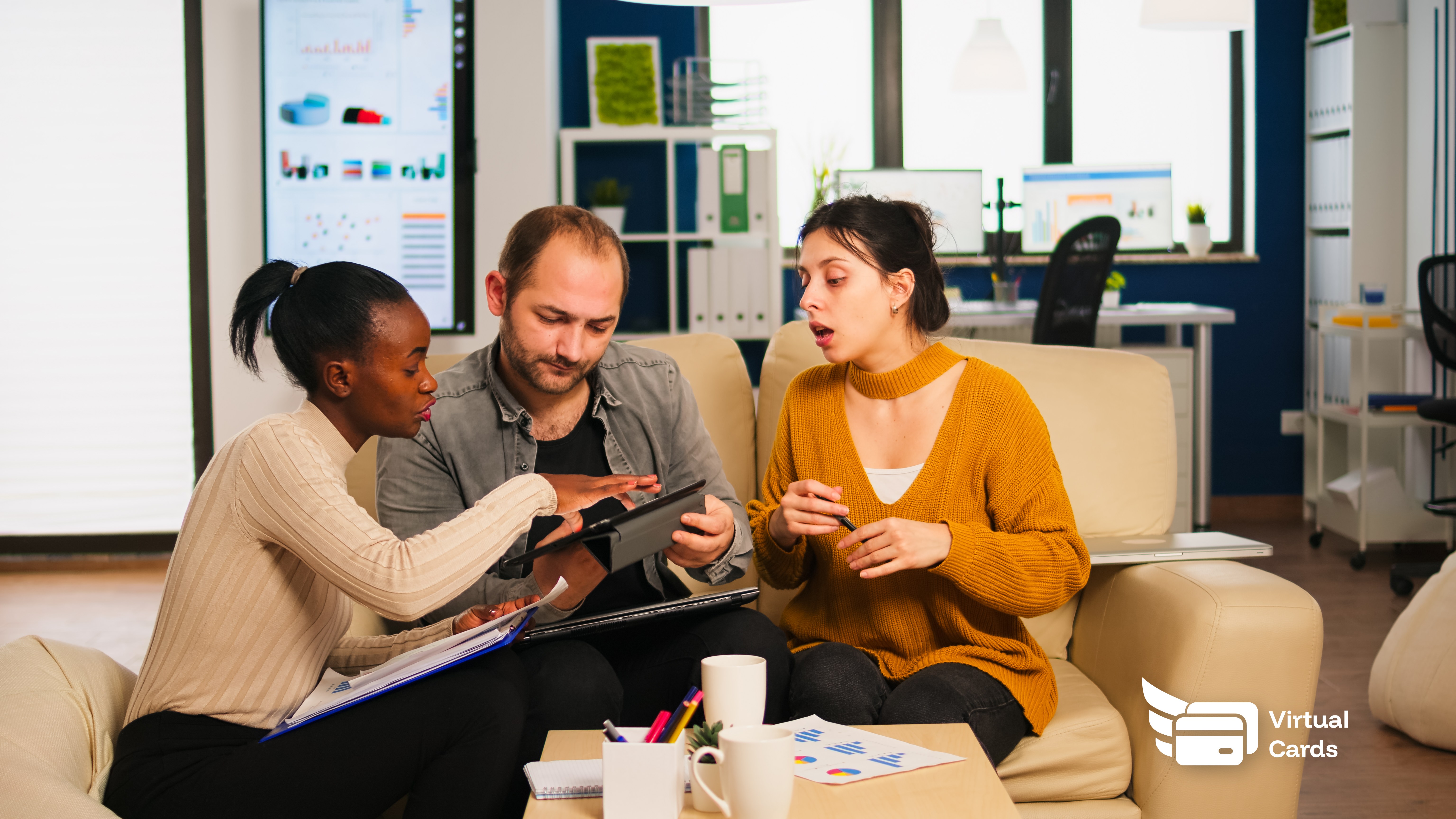 A diverse agency team in a meeting room reviewing client campaign budgets on a laptop, with virtual cards on screen representing each client account.