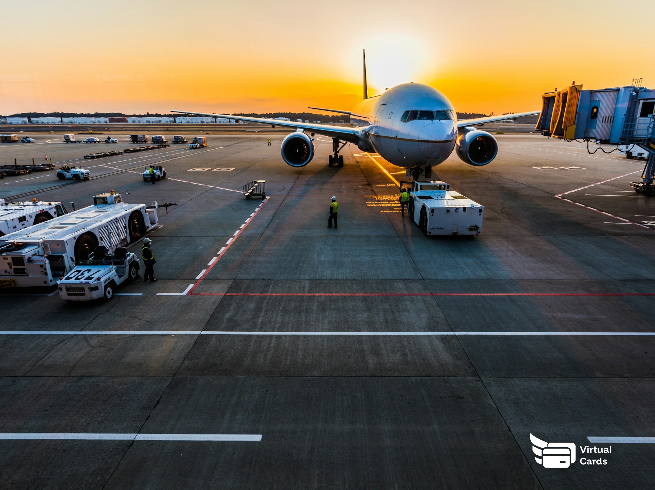 A passenger jet at the gate at sunset with ground crew, representing business travel on per-trip virtual Visa cards.