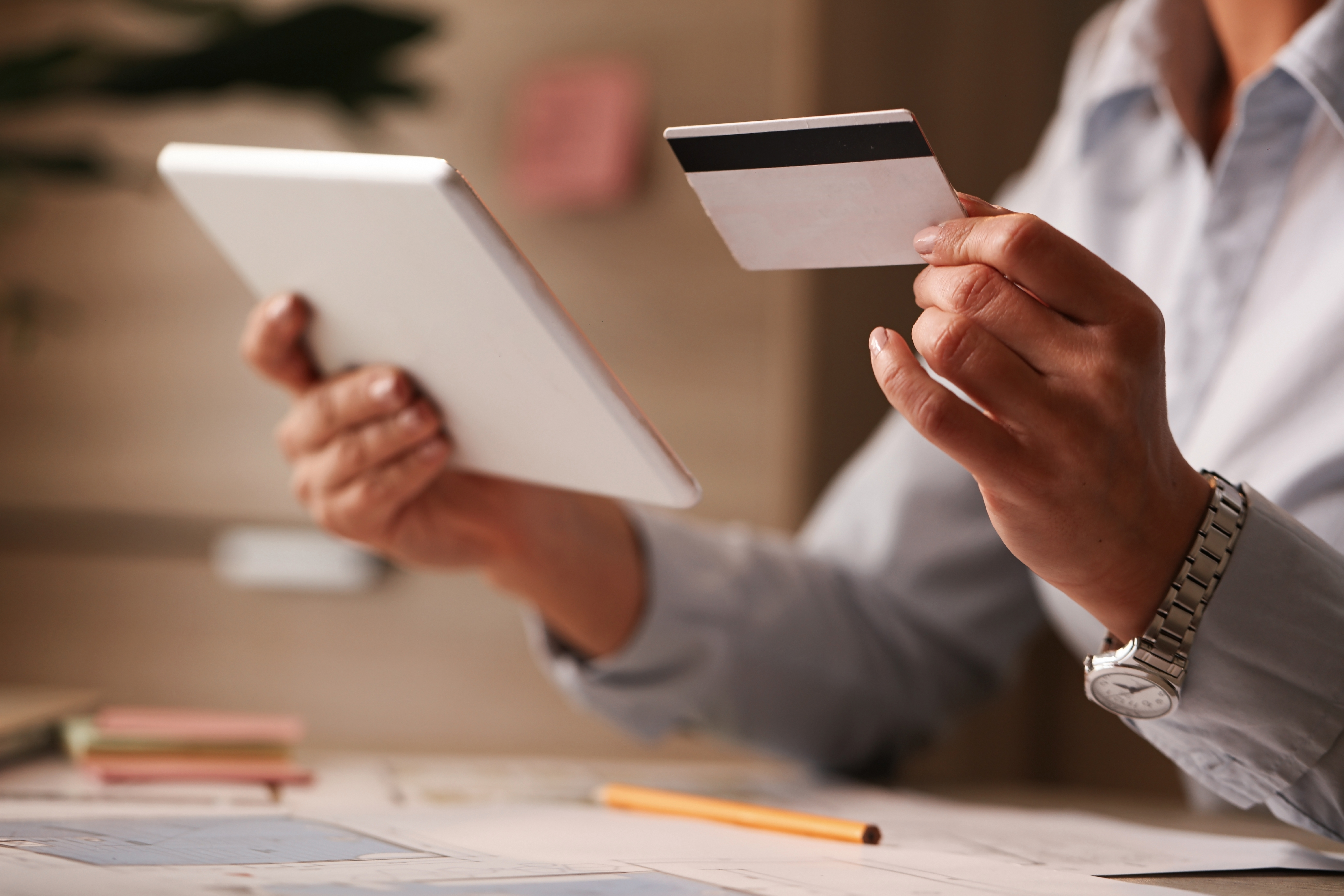 Businesswoman reviewing expense card and tablet at her desk