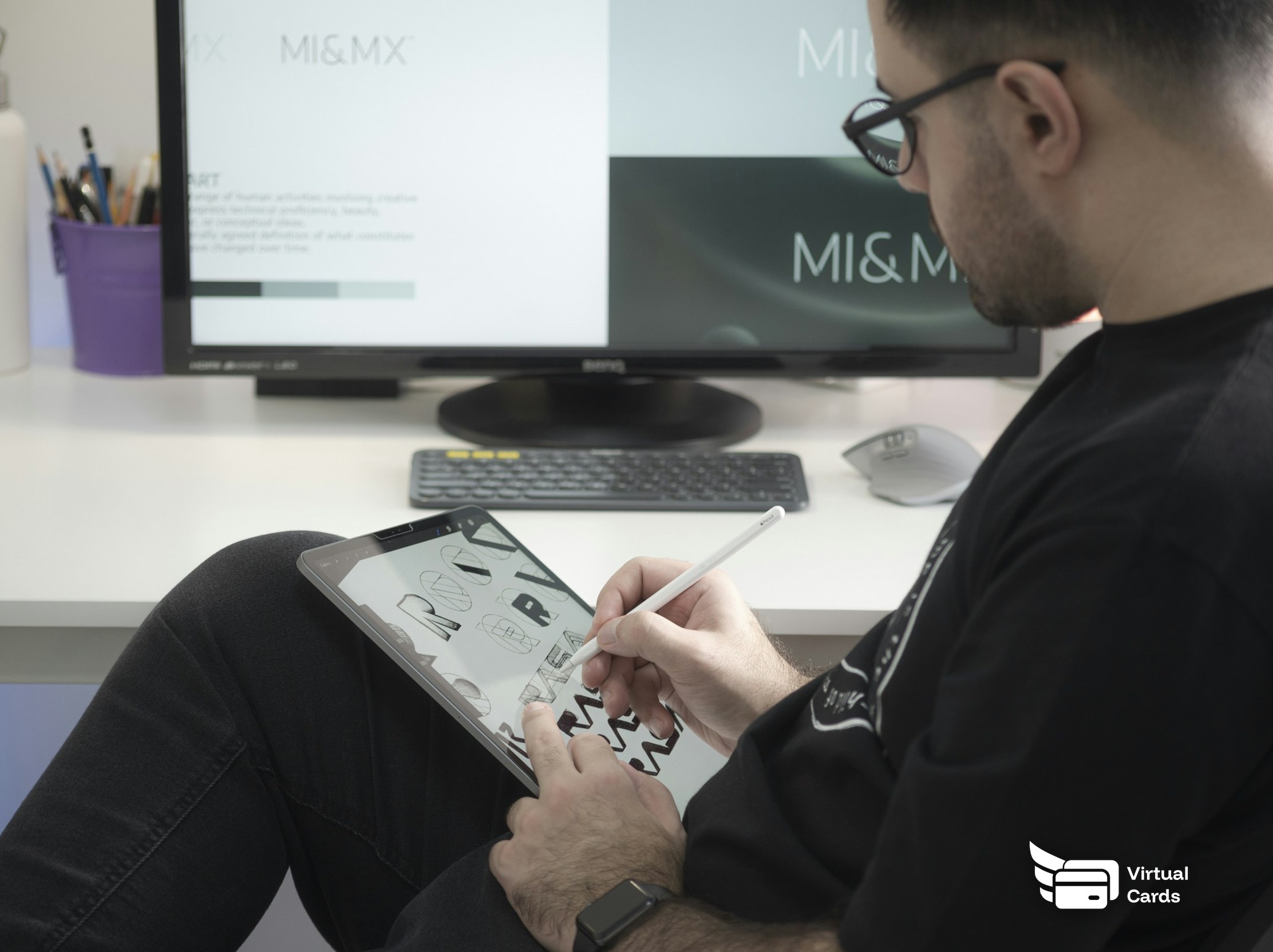 A freelance designer drawing on a graphics tablet with a stylus at a desk.