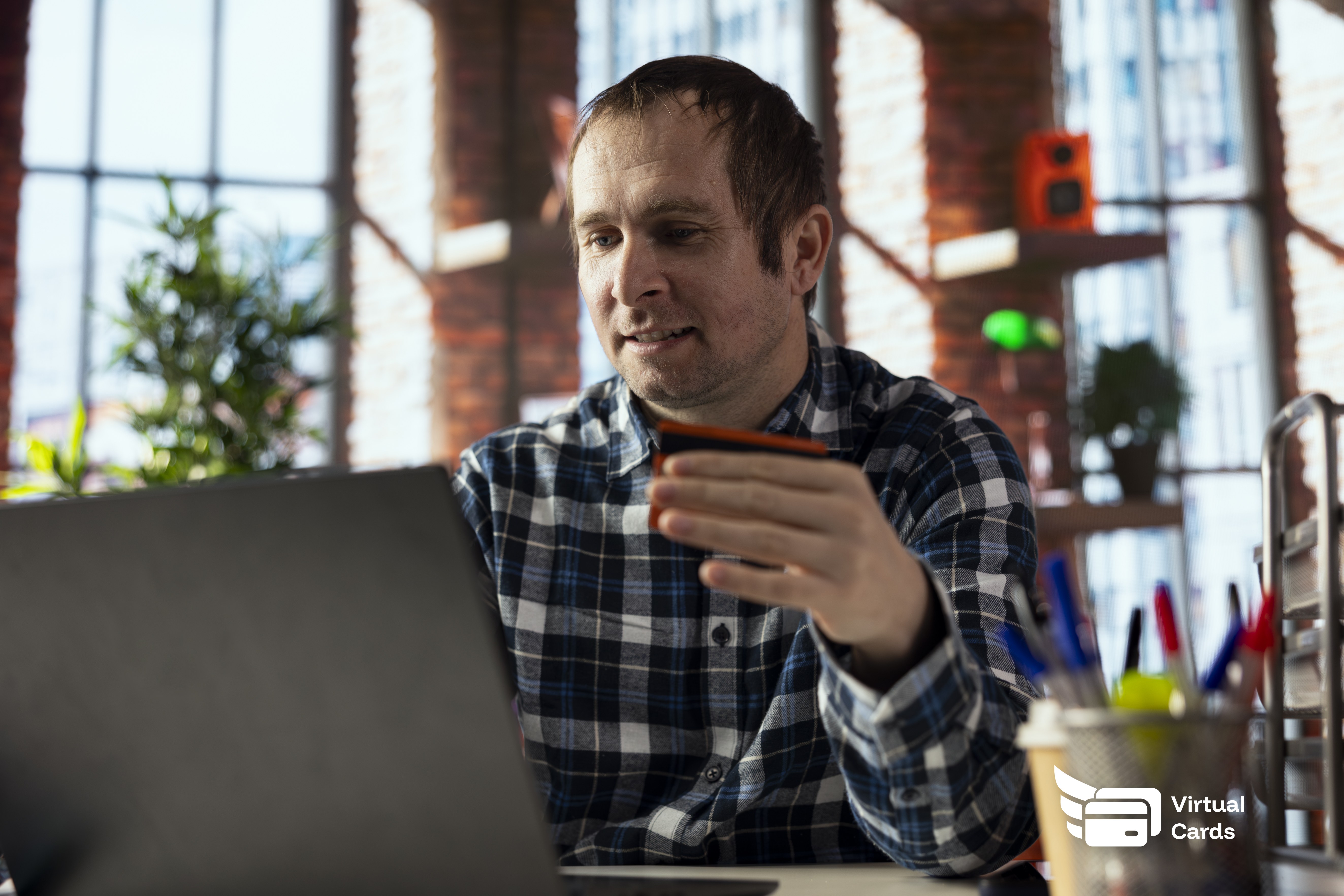 A professional at a desk entering a virtual card number to pay a freelancer online, keeping the main business card secure in the background.