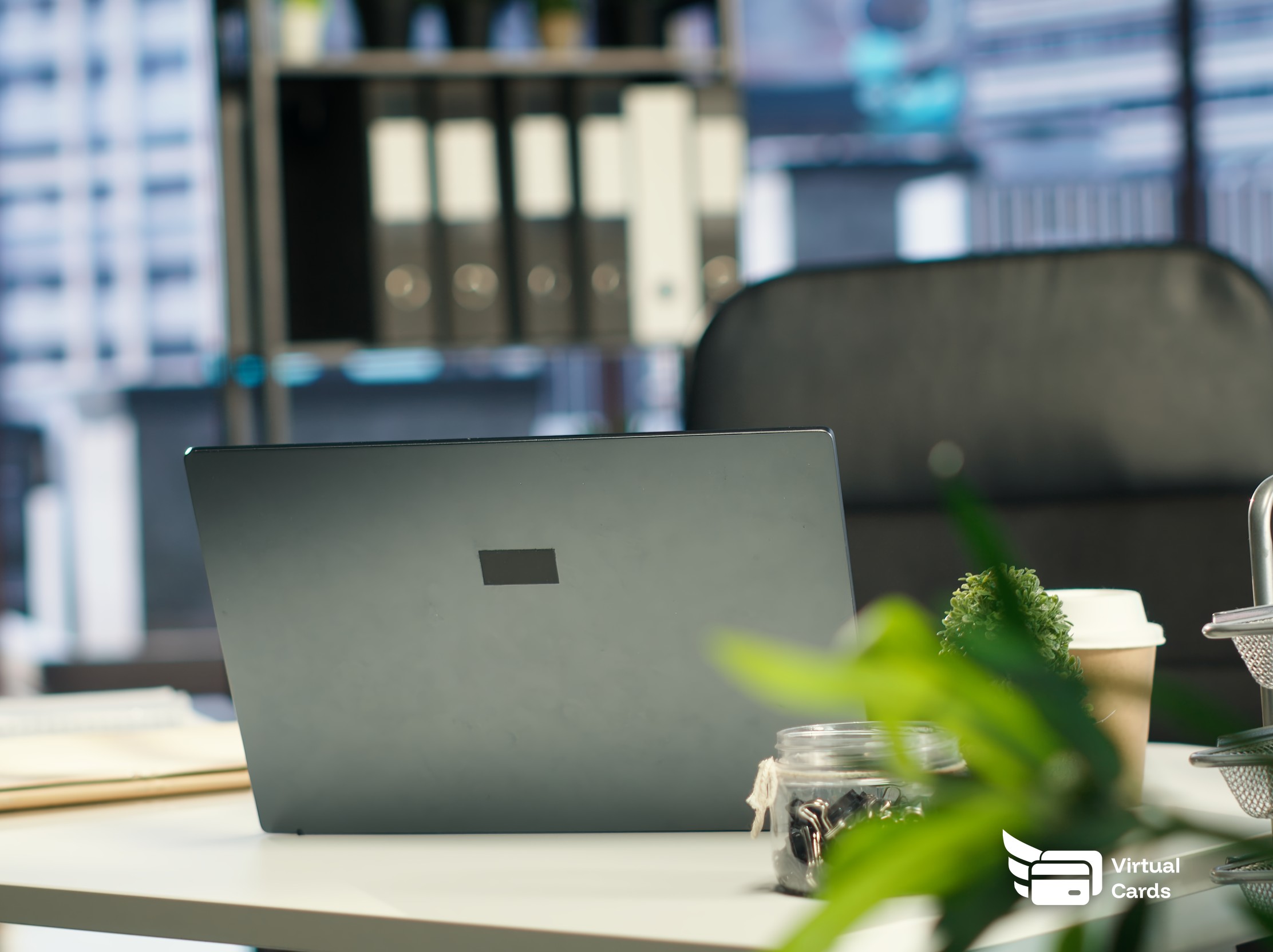 A closed laptop and an empty office chair at a vacated desk, representing an employee's SaaS subscriptions that still need to be reviewed and cut off after they leave.