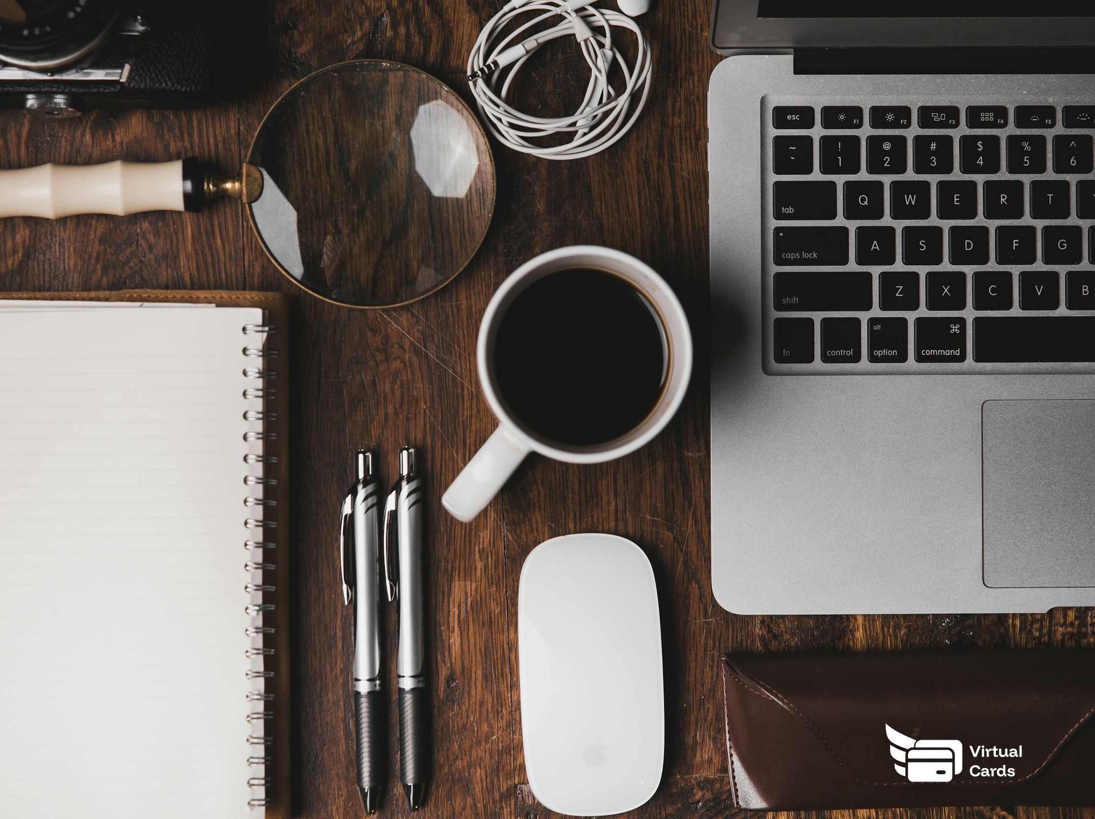 An overhead view of a tidy desk with a laptop, coffee, and notebook, representing managing SaaS subscriptions with virtual Visa cards.