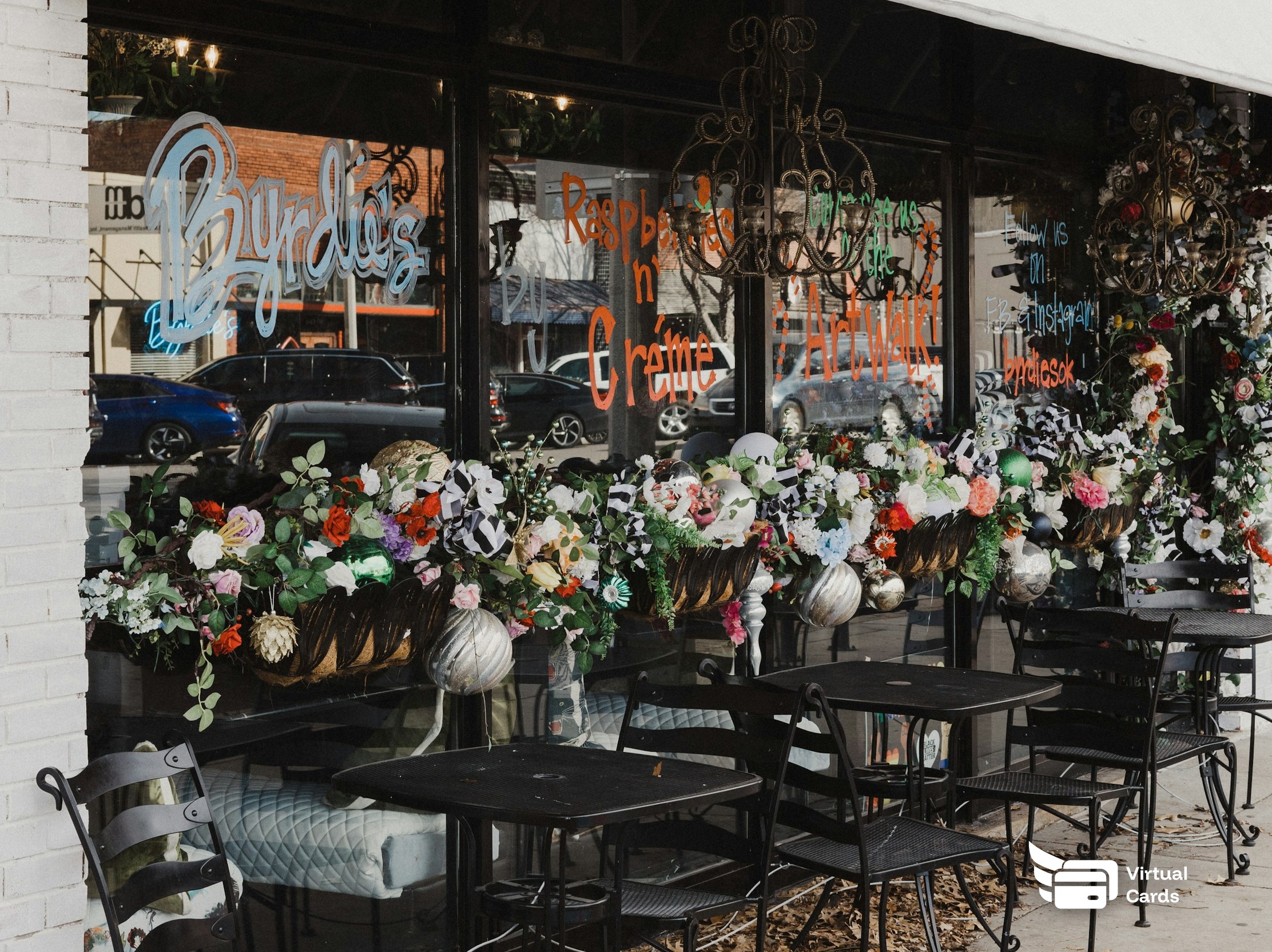 Tables and chairs set up outside a small neighborhood flower shop.