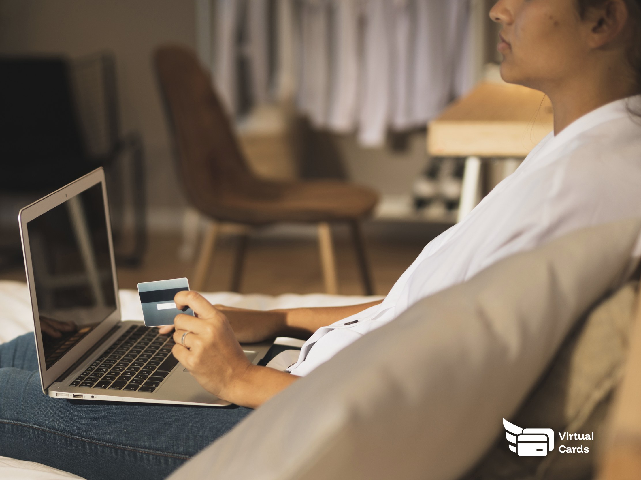 A person's hands near a laptop holding a card while reviewing an online form, representing the choice between a business virtual Visa card and a store gift card